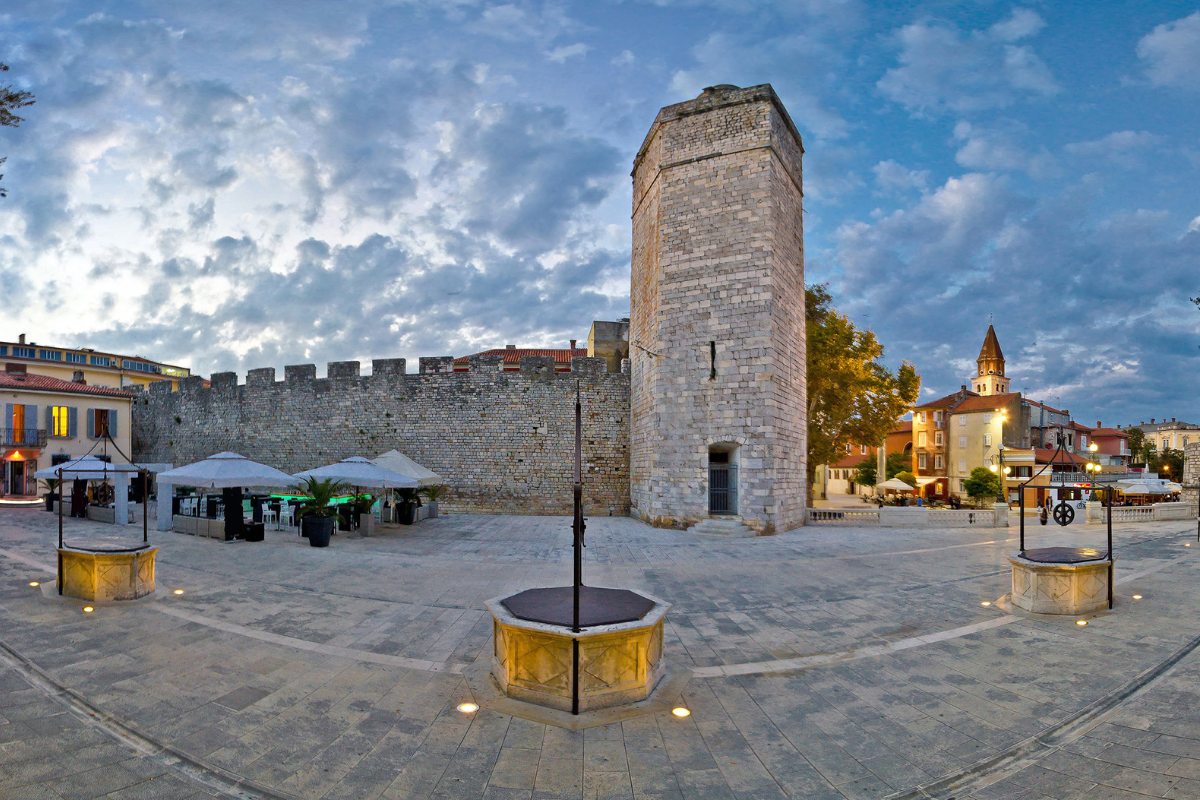 An evening shot of Five Wells Square in Croatia with an ancient stone tower, medieval walls, decorative wells