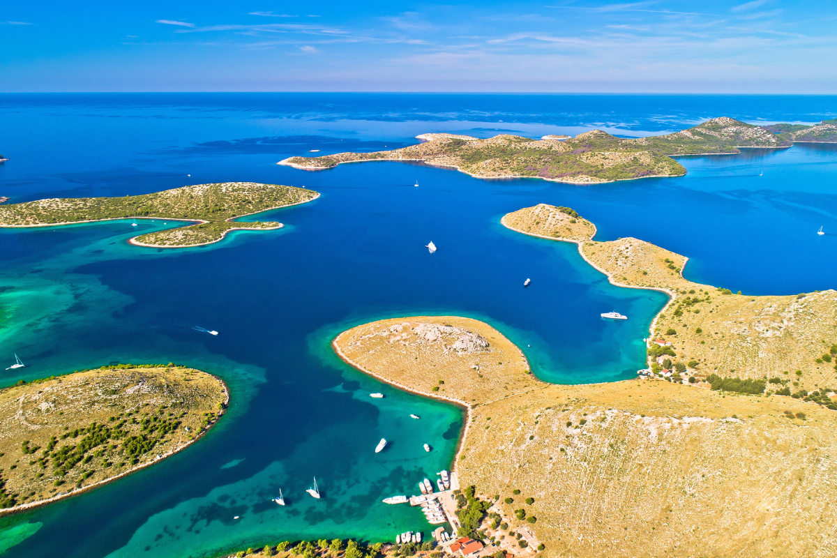 An aerial view of the Kornati Islands in Croatia with blue water, small green islands, and boats under a clear sky.