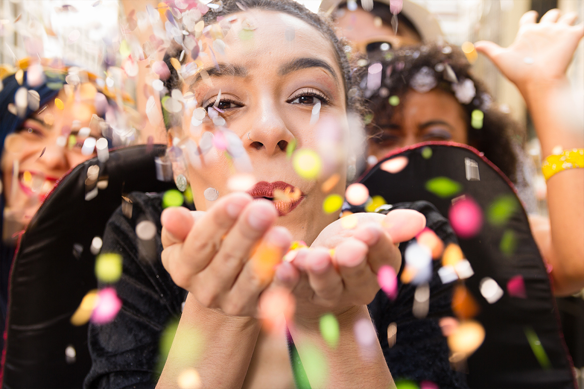A woman blows confetti into the camera