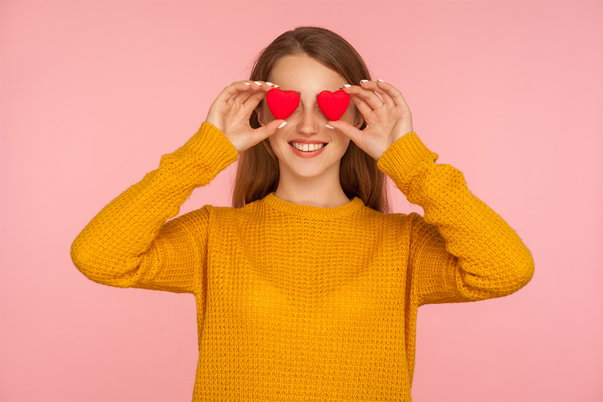 A single girl holds up a love heart to each eye