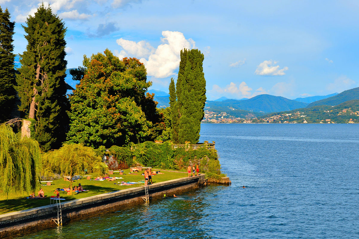 Persone che si rilassano e prendono il sole su una spiaggia erbosa sul Lago Maggiore