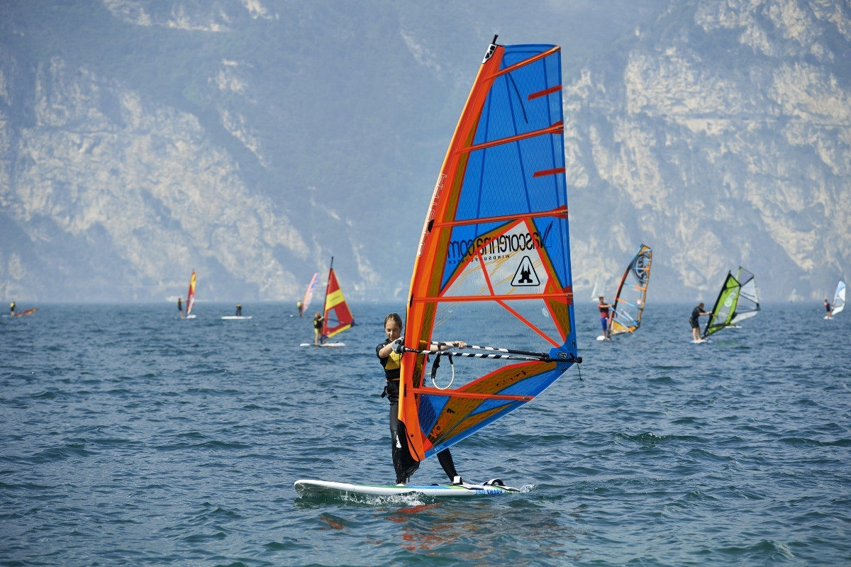 Una donna che si diverte a praticare il windsurf sul lago di Garda, in Italia, dal centro internazionale di windsurf di Nago-Torbole