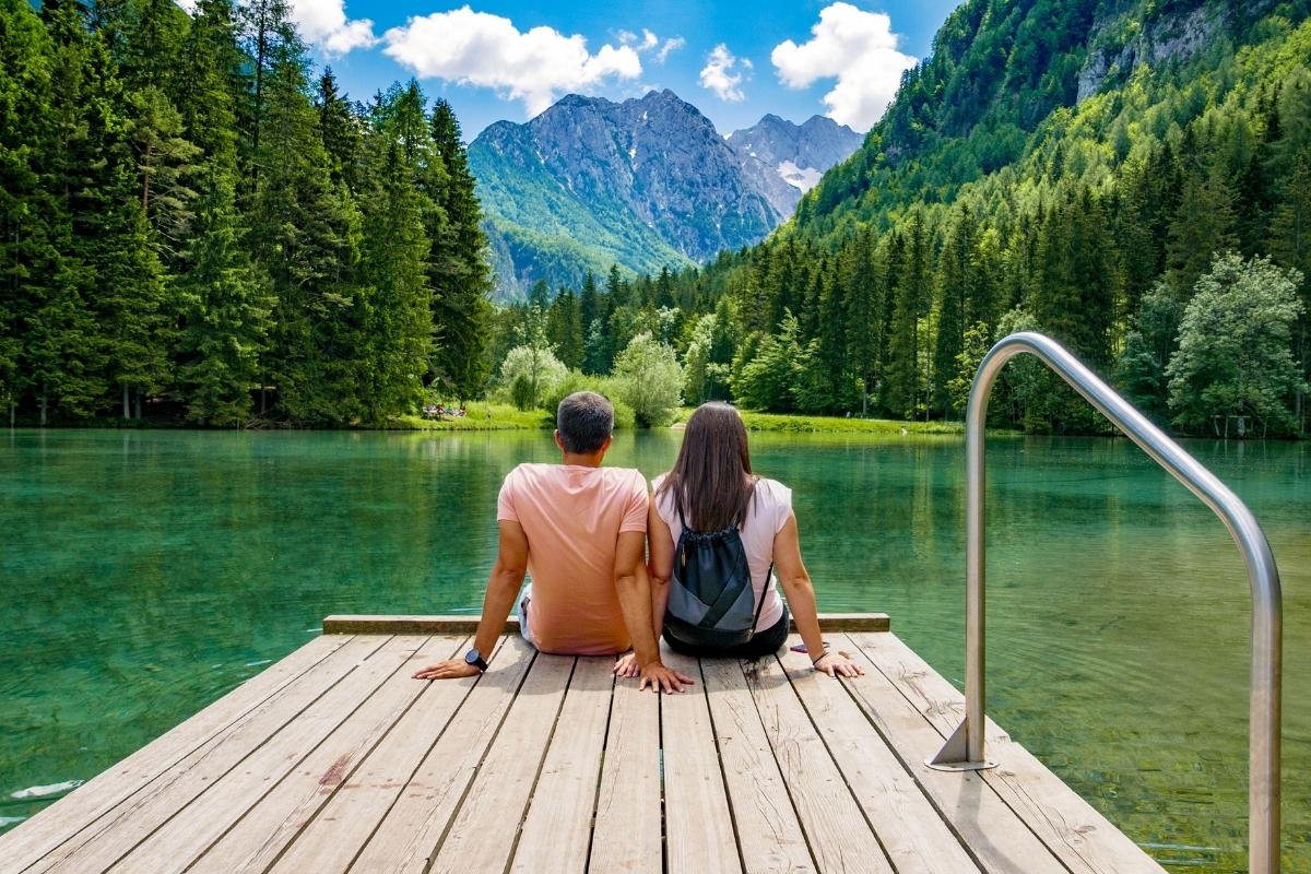 Un uomo e una donna si godono la vista delle montagne che circondano il lago Planšarsko nel villaggio di Jezersko, Slovenia