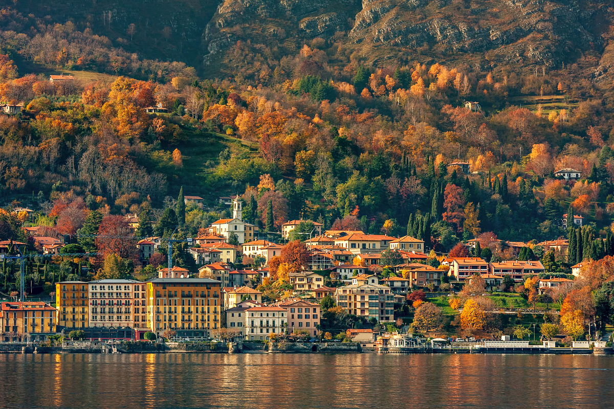 Il Lago di Como in autunno, con una città sulle rive del lago immersa in splendide tonalità di cremisi, ocra e verdi.