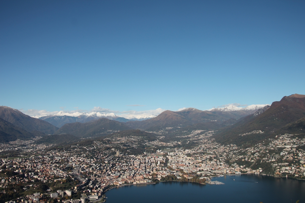 Beautiful aerial shot of the Swiss city of Lugano, in Ticino, with snow peaked mountains and ice cold lake