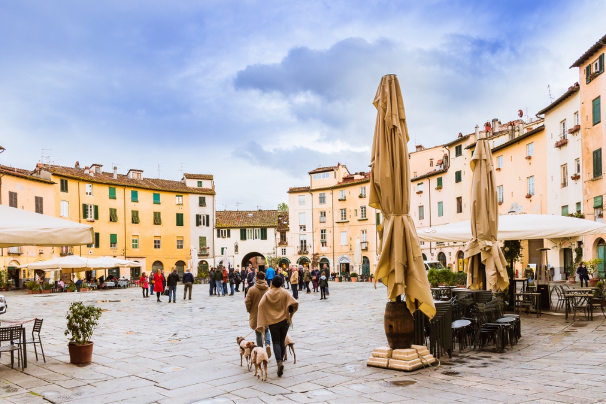 Cityscape with group of tourists and people walking with dogs on the main square under the blue sky, Lucca, Tuscany