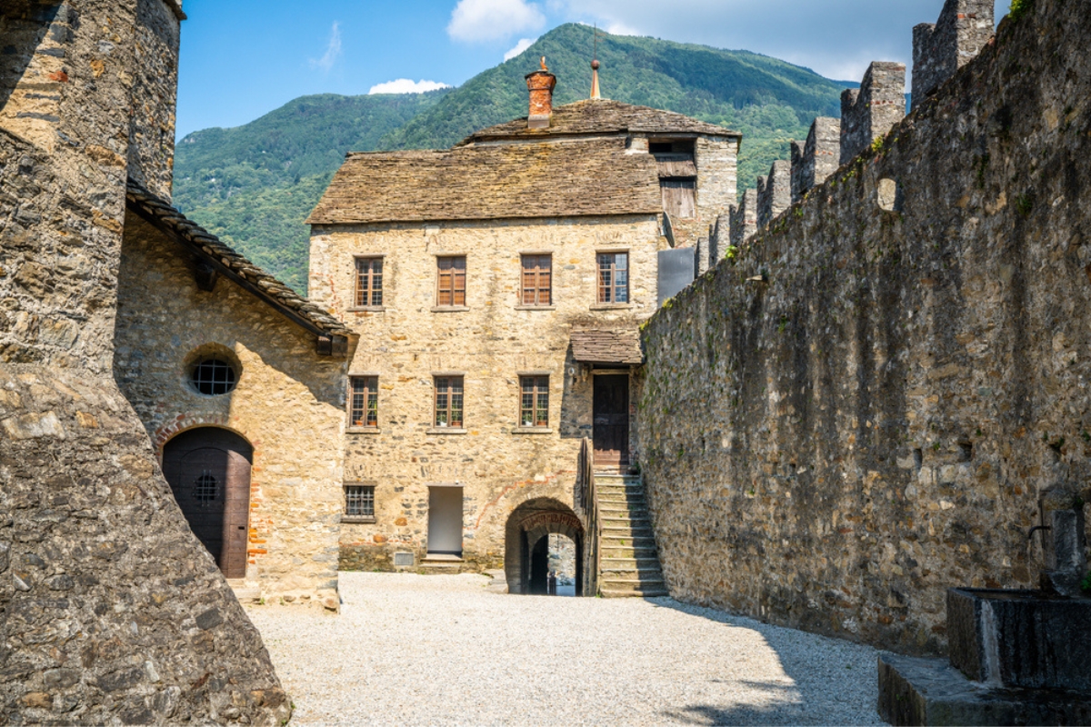 Cortile e ingresso Castello di Montebello con edificio e mura e montagna sullo sfondo a Bellinzona, Ticino, Svizzera