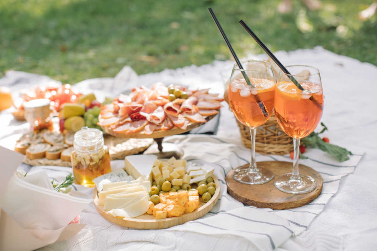 Traditional Italian aperitif and tasty food on blanket in the park