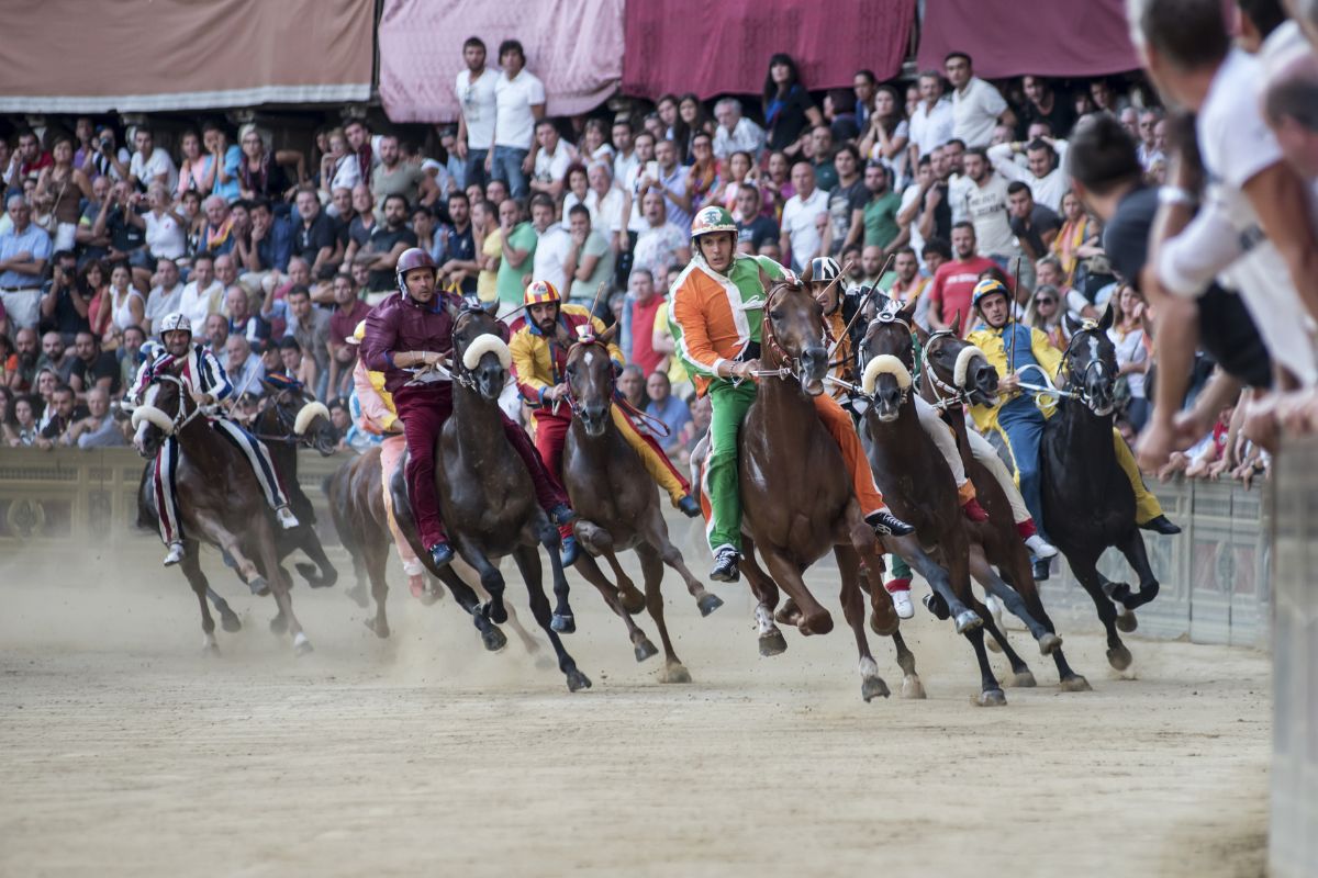 I fantini si sfidano sui loro cavalli al famoso Palio di Siena in Piazza del Campo