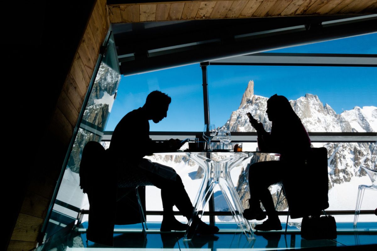Due persone sedute al ristorante in un tavolo panoramico con vista sul famoso Monte Bianco, Skyway, Valle d'Aosta, Italia