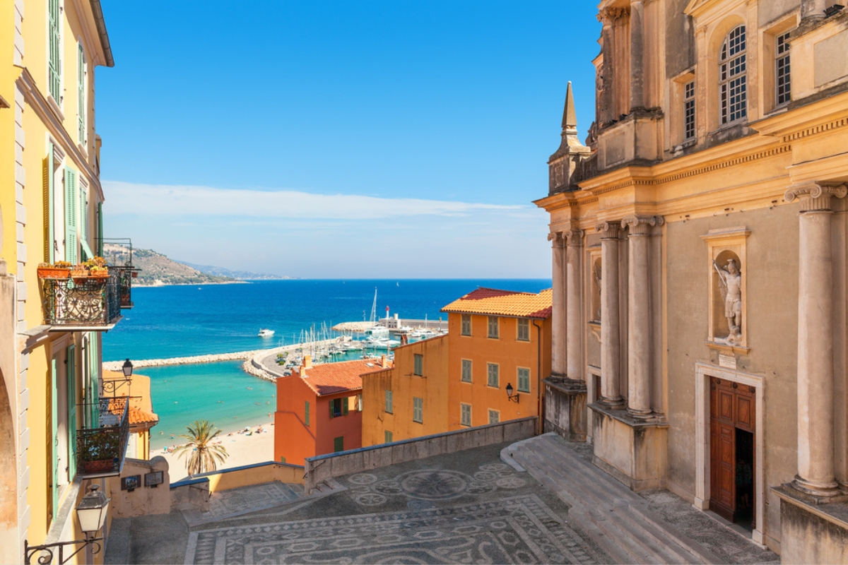 La piazza tra l'antica chiesa e le case colorate con vista sul Mar Mediterraneo a Mentone, Francia