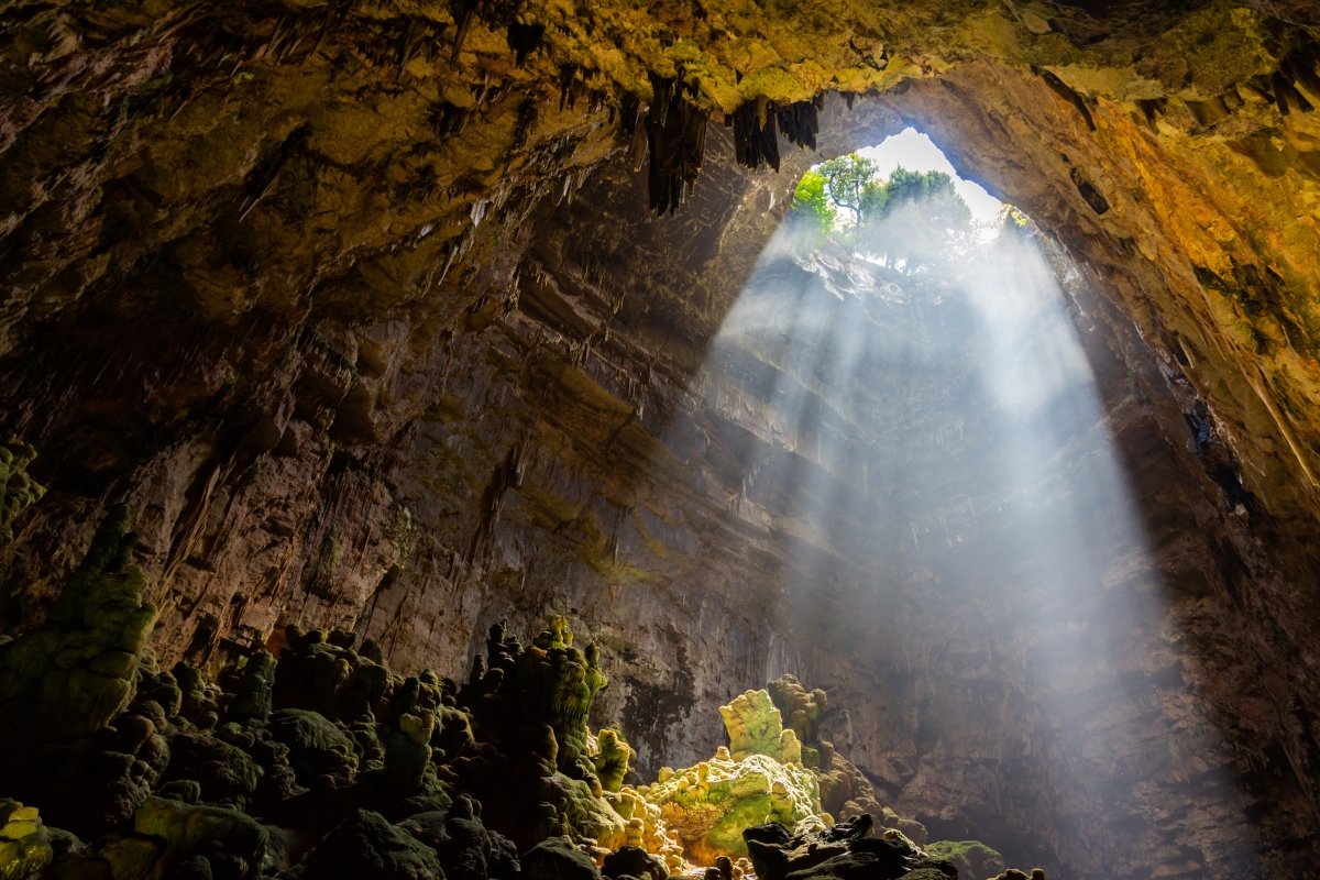 L'interno delle grotte di Castellana con stalagmiti e stalagtiti e un foro sul soffitto