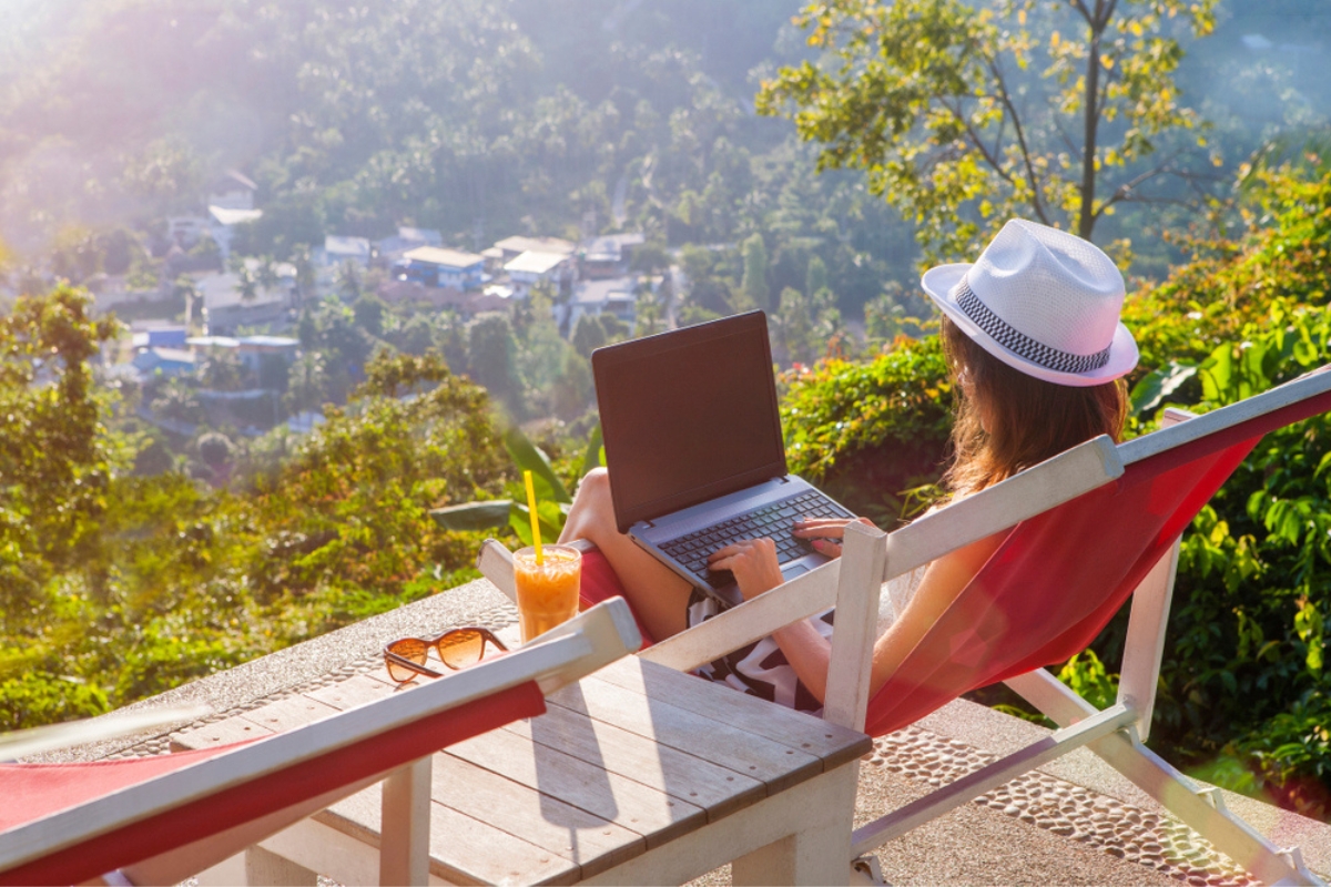 Ragazza freelance che lavora al laptop con una bella vista e un cocktail