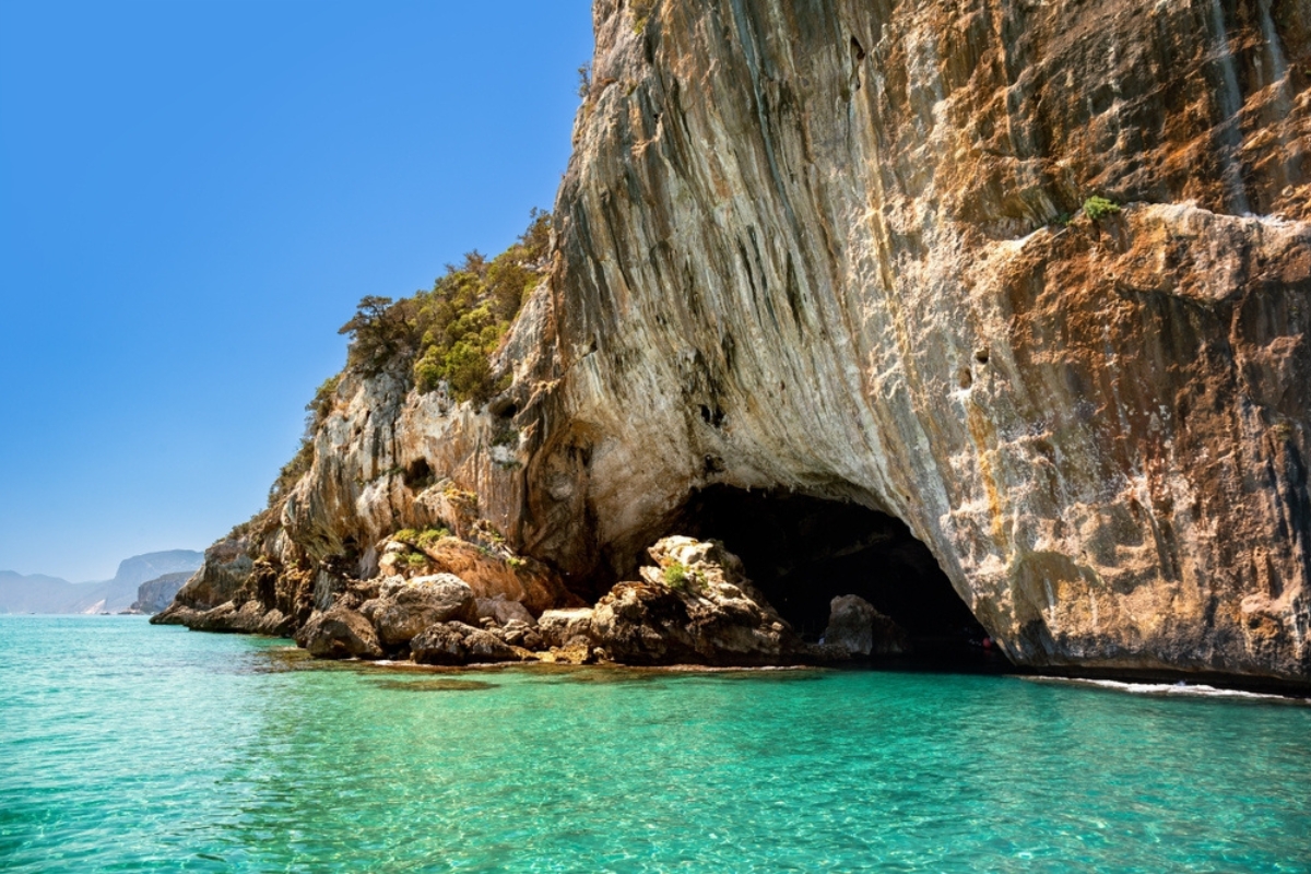 Scogliere e acque turchesi vicino alla Grotta del Bue Marino vista dal mare, Sardegna, Italia