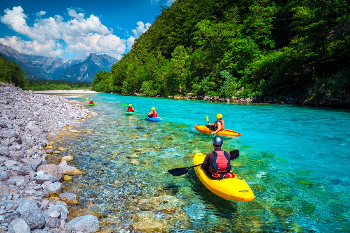 Kayakers in colorful life jacket paddling and exercising on the emerald color Soča river, Bovec, Triglav National Park, Slovenia, Europe
