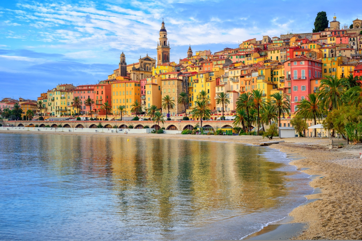 Spiaggia di sabbia con sullo sfondo, la colorata città vecchia di Mentone in Costa Azzurra, Francia