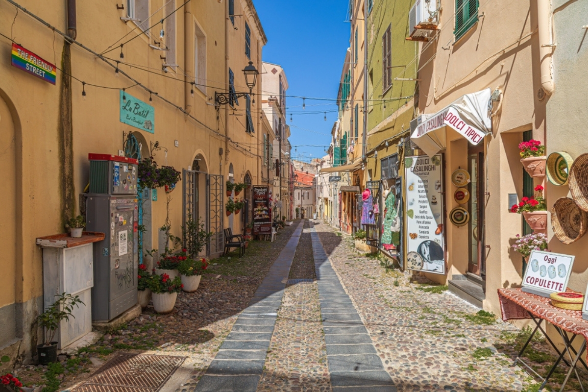 Strada medievale pittoresca, tipica sarda, con piccoli negozi di souvenir tradizionali ad Alghero, Sardegna