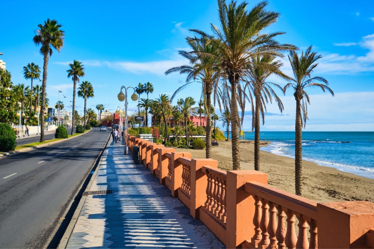 Sandy beach, Mediterranean Sea, palm trees view next to seafront promenade in Benalmadena town
