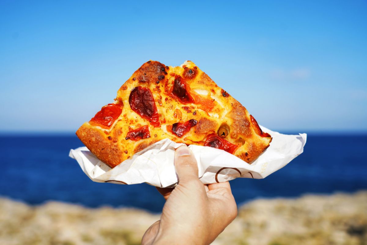 Focaccia barese slice with Mediterranean sea on background
