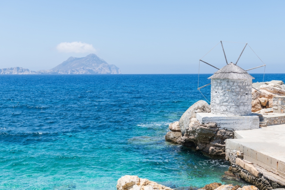 Traditional whitewashed windmill in the port of Aegiale or Aigiali on the greek island of Amorgos on a bright sunny day