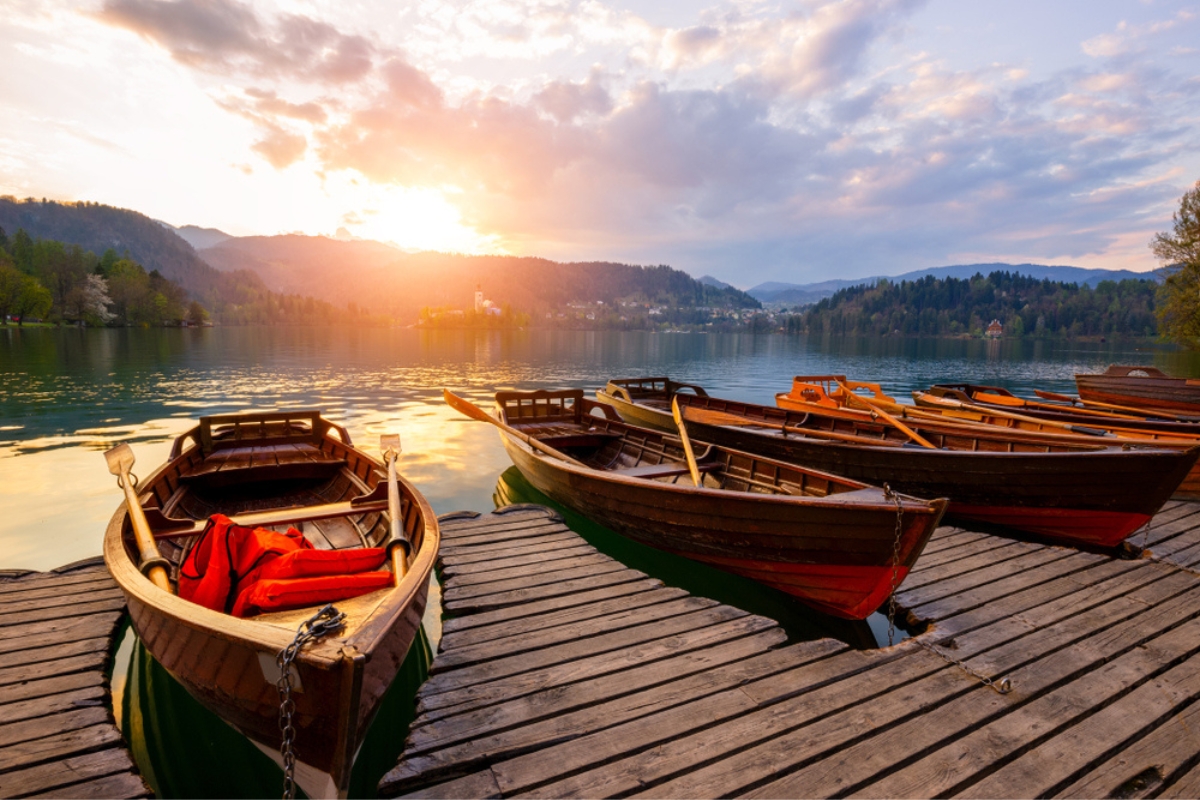 Traditional wooden boats Pletna on the backgorund of Church on the Island on Lake Bled suring sunset, Slovenia. Europe.