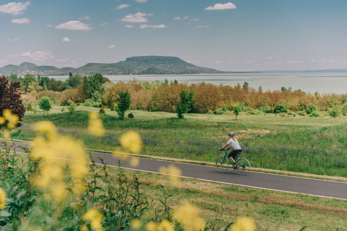 Una donna in bicicletta mentre attraversa un percorso lussureggiante sul lago Balaton, in Ungheria