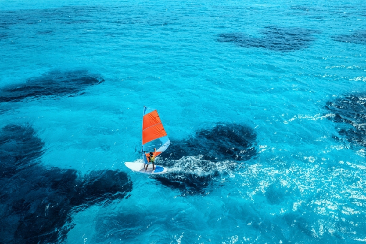 Vista aerea di un windsurfer sul mare blu in una soleggiata giornata estiva. Sardegna, Italia