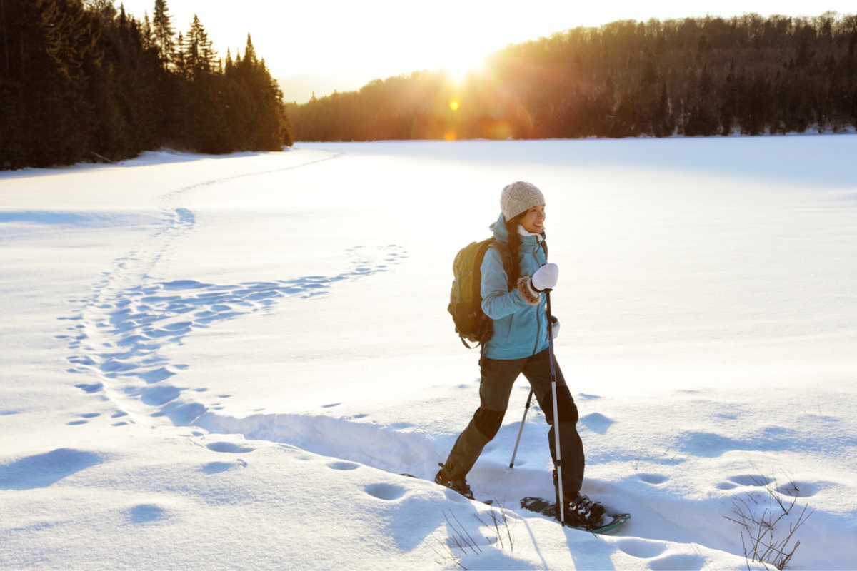 Woman with backpack and snowshoes in the coniferous forest